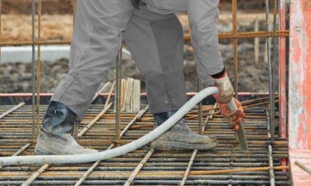 A Ram Jack worker operating a concrete pump, directing the flow of concrete.