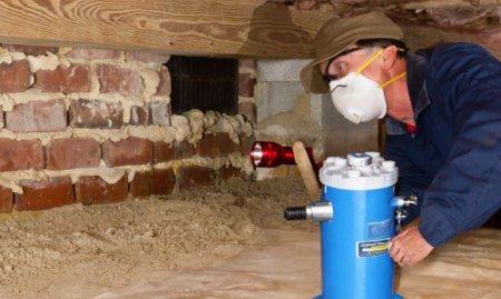 Ram Jack worker carrying sump pump into crawl space.