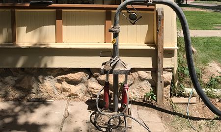 A pump set up to inject a grout mixture under a sunken concrete slab.