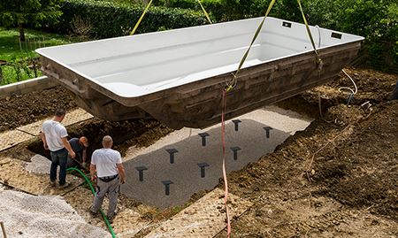 Featuring foundational supports installed underneath a pool being lowered in to the ground