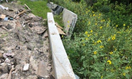 A newly installed retaining wall with specialized brackets and helical piles.