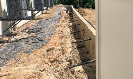 A retaining wall actively being reinforced with helical tie-back anchors.