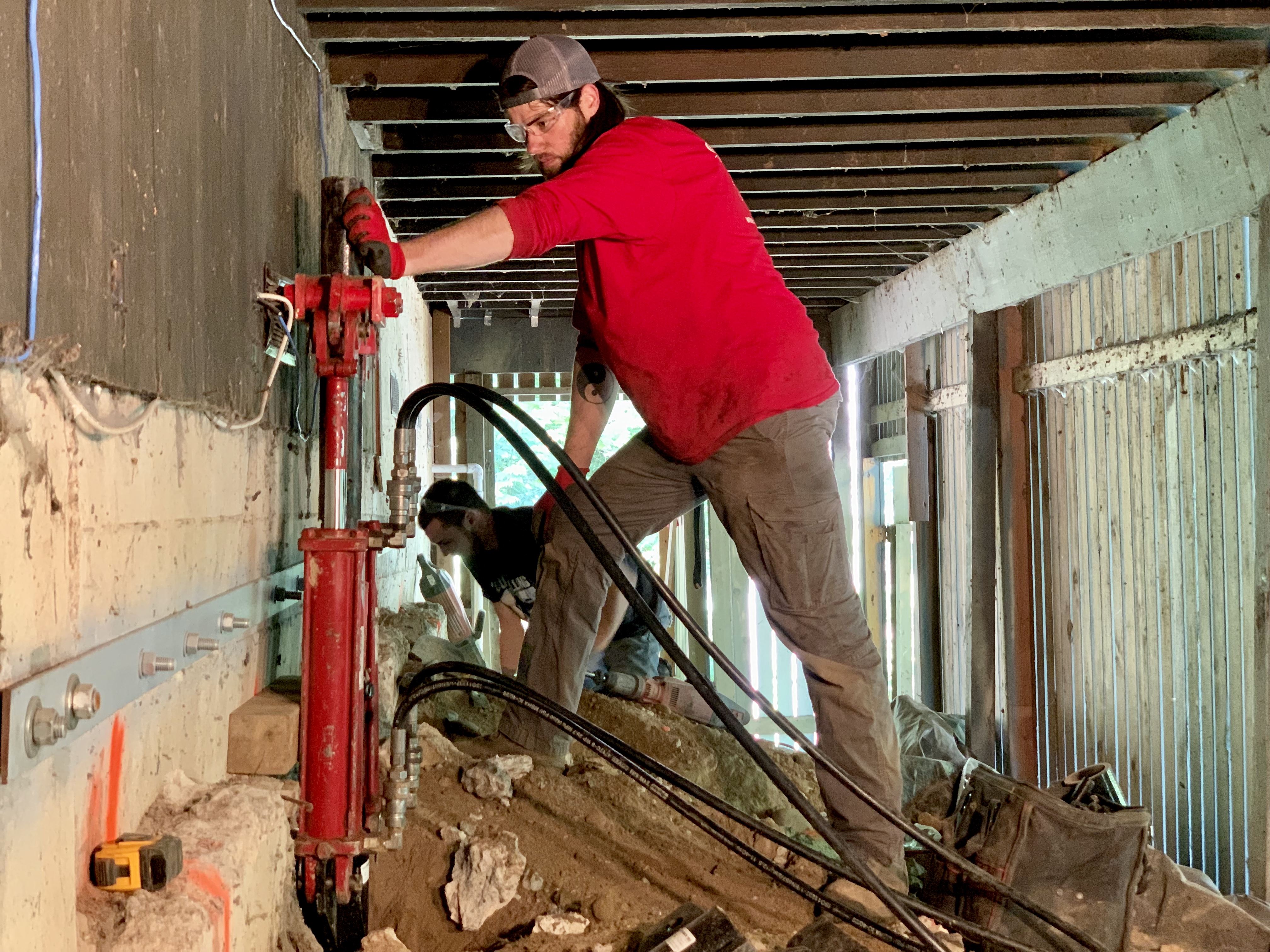 A construction worker operating heavy machinery to drive a pile deep into the ground.